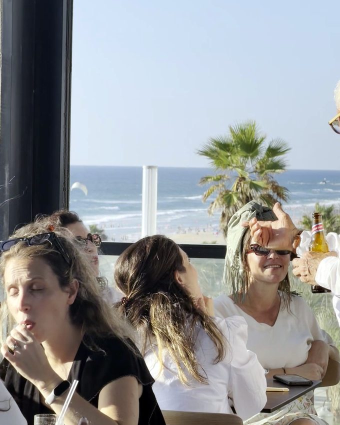 אורחות יושבות סביב שולחן מול חלון הים באירוע